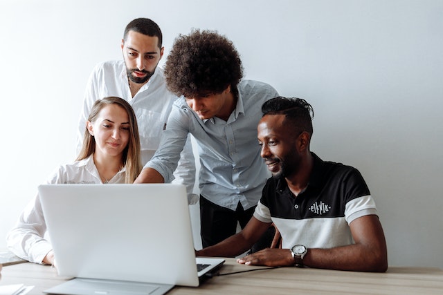 four people looking over a marketing plan on someones laptop